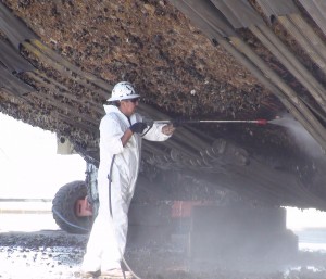dockyard worker cleaning barnacles from a boat hull