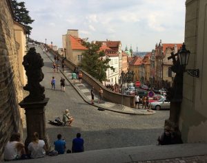 Prague street scene with people sitting on steps