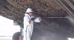 dockyard worker cleaning barnacles from a ship hull