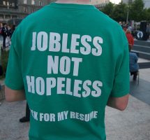 A man wearing a t-shirt: the back reads 'jobless not hopeless, ask for my resume'