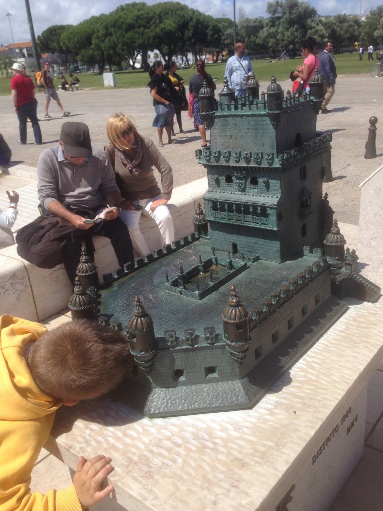 A young boy peers into the model beneath its battlements