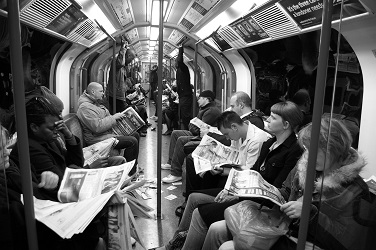 commuters on the London Underground reading their newspapers