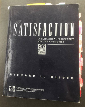 A battered copy of Richard L. Oliver "Satisfaction: A behavioral perspective on the consumer" with tons of index flags sticking out
