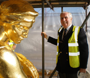 On the left, the head and shoulders of a gilded statue - the head is about a third the height of a person. On the right, a smiling elderly John Sankey. 