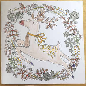 A card with a pre-printed design of a reindeer surrounded by a wreath of foliage and snowflakes, coloured in shades of brown and green with some silver